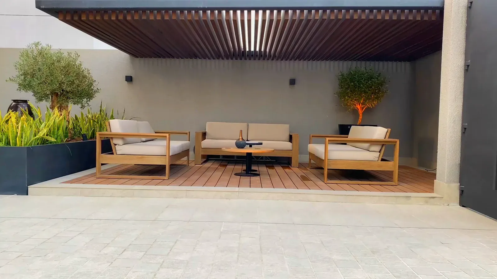 A finished outdoor living space with seating under a slatted timber pergola