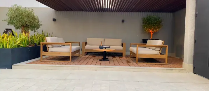 A finished outdoor living space with seating under a slatted timber pergola